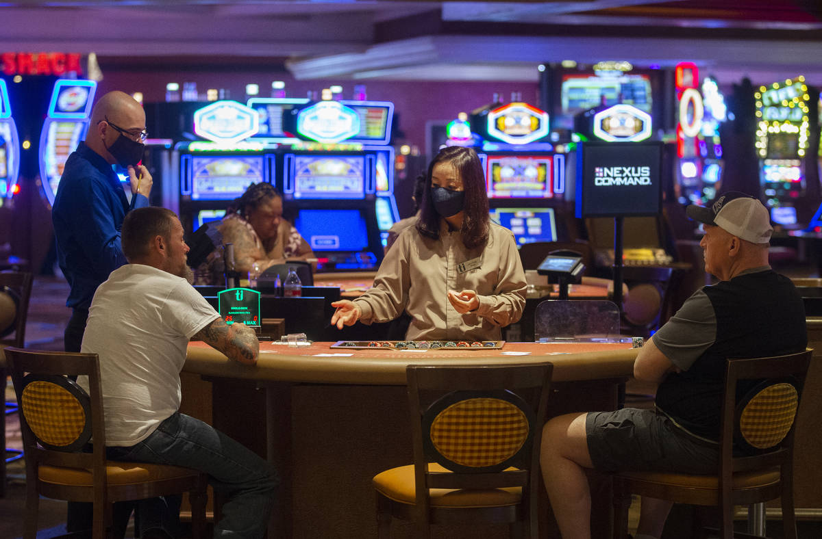 Una dealer con un cubrebocas habla con jugadores de blackjack en Treasure Island el jueves, 4 d ...