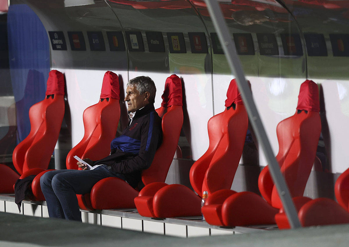 El entrenador en jefe del Barcelona, Quique Setien, se sienta en el banco antes del inicio de l ...