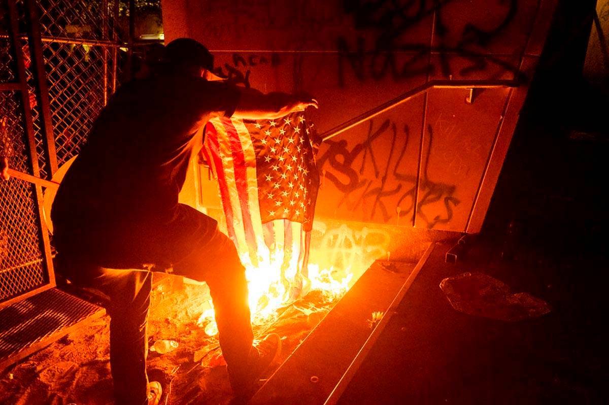 Un manifestante de Black Lives Matter quema una bandera estadounidense frente al Palacio de Jus ...
