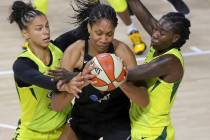 A'ja Wilson, de las Aces de Las Vegas, centro, es interceptada por Alysha Clark de Seattle, izq ...