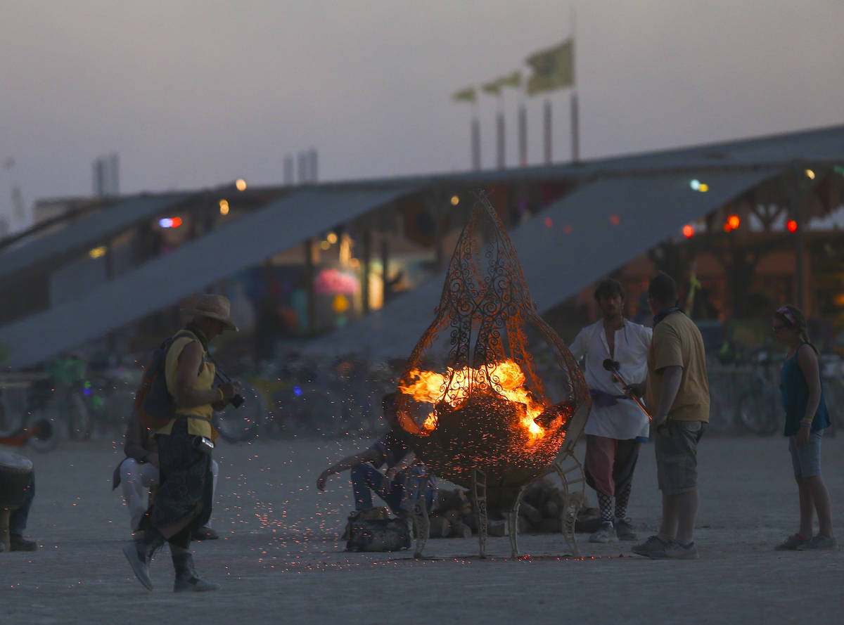 Los asistentes se reúnen alrededor de un foso de fuego durante Burning Man en el desierto de B ...