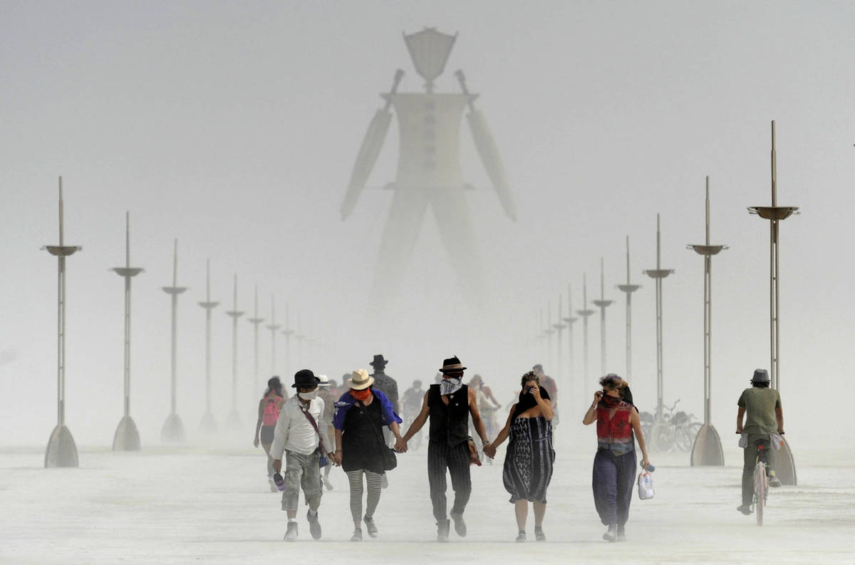 Los participantes de Burning Man caminan entre el polvo en el evento anual en el desierto de Bl ...