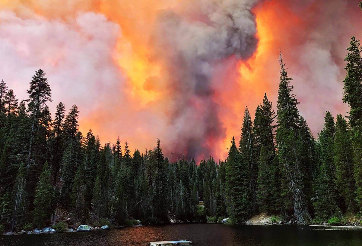 Humo del Creek Fire se eleva más allá de una cresta, como se vio en el lago Huntington el sá ...