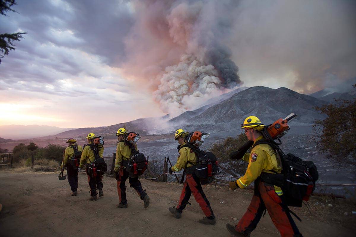 Miembros de los bomberos caminan en fila durante un incendio forestal en Yucaipa, California el ...