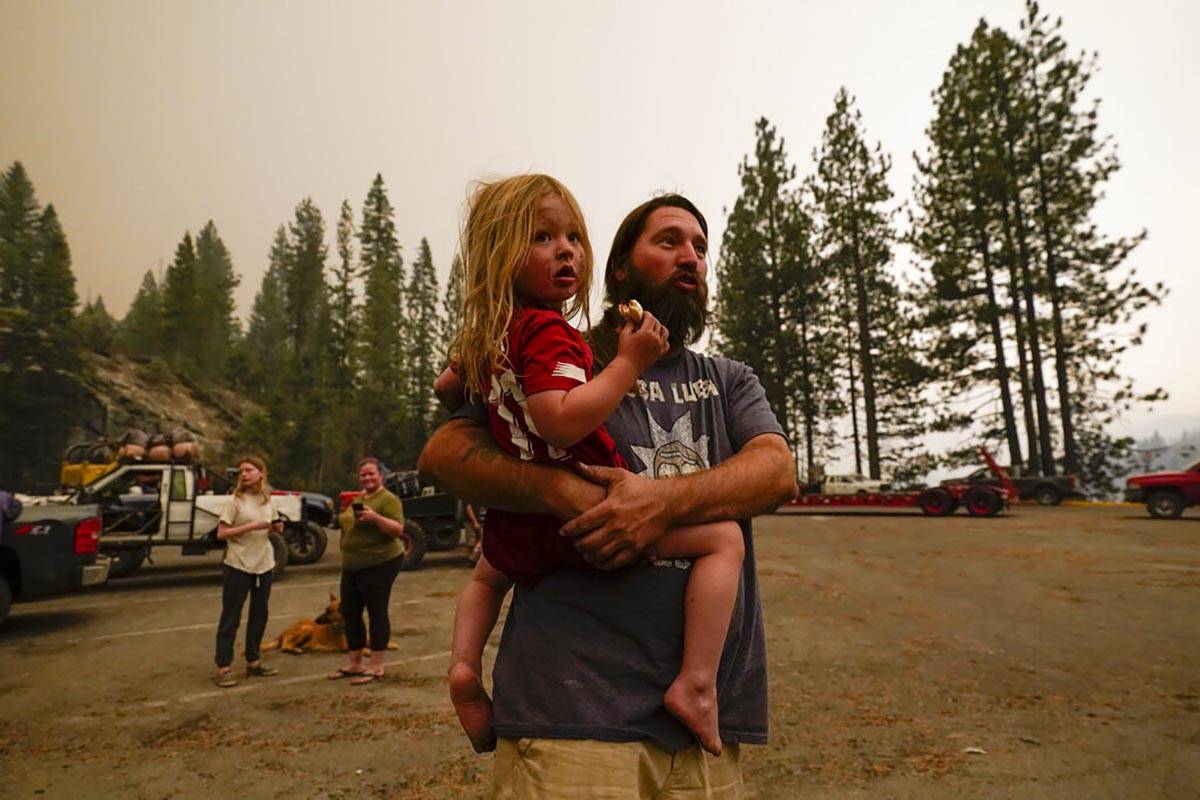 Jeremy Hedrick sostiene a su hijo Jeep mientras el humo del Creek Fire llena el aire en un puer ...