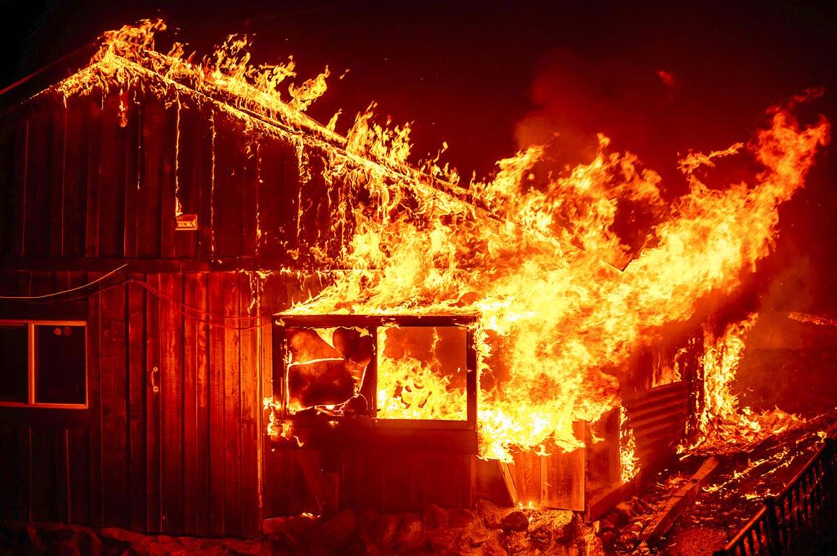 Las llamas se disparan desde una casa mientras el fuego del Bear Fire arde a través del área ...