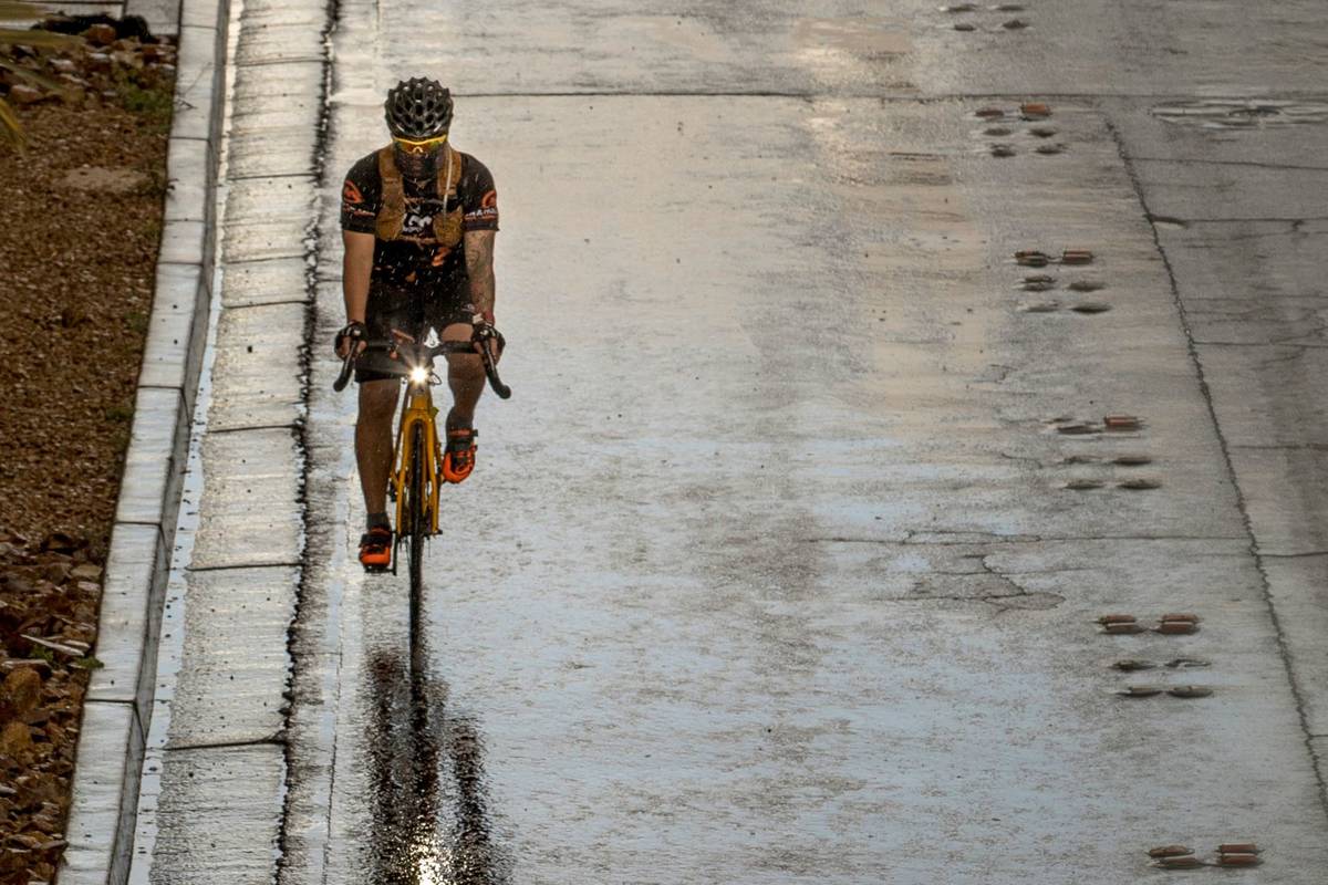 Un ciclista con cubrebocas transita bajo la lluvia en el Strip de Las Vegas pasando por el cent ...