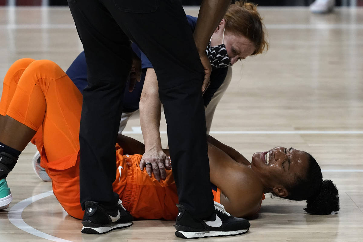 Un entrenador ayuda a Alyssa Thomas (25) del Connecticut Sun después de que se lesionara en la ...
