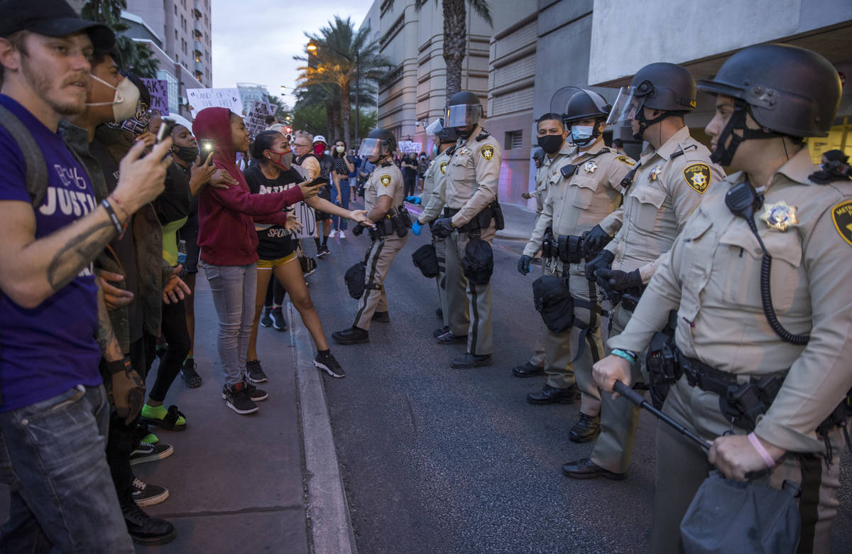 La policía de Las Vegas observa como los manifestantes se enfrentan a ellos mientras marchan a ...