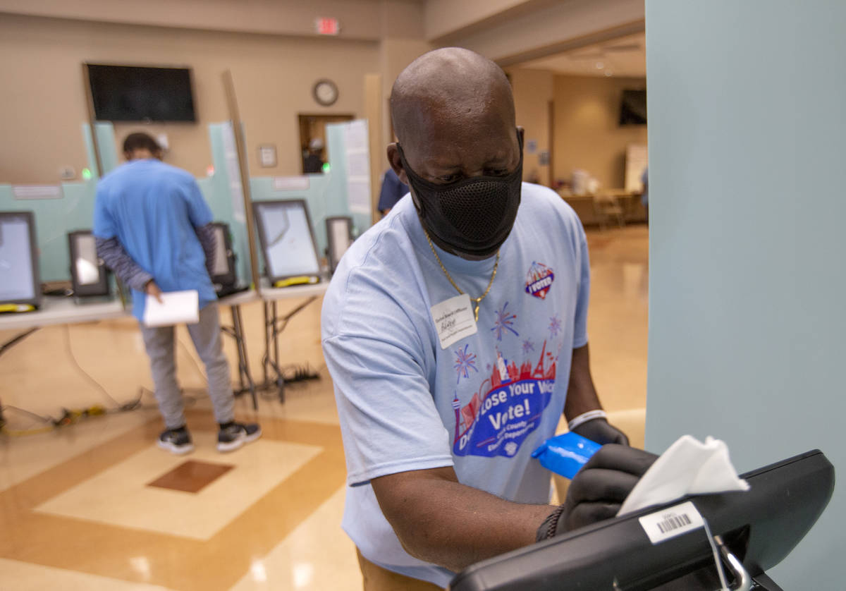 Rodney Jefferson limpia una máquina de votación en el Doolittle Community Center durante la v ...
