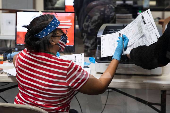 Una trabajadora electoral del Condado Clark revisa una boleta mientras se prepara para escanear ...