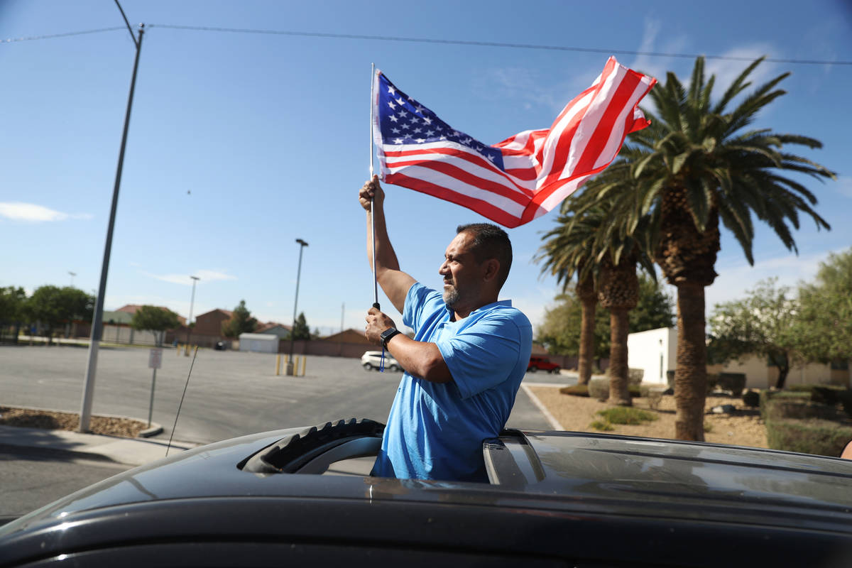 Juan Prillwitz ondea una bandera estadounidense mientras participa en un desfile de campaña pa ...