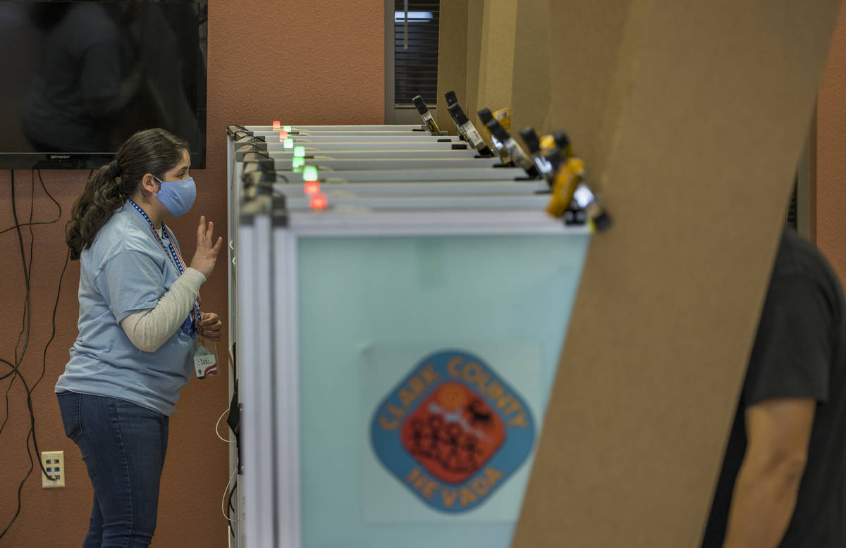 Una trabajadora electoral da instrucciones a un votante mientras está en una mostrando la ocup ...