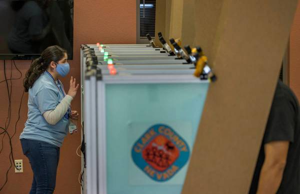 Una trabajadora electoral da instrucciones a un votante mientras está en una mostrando la ocup ...