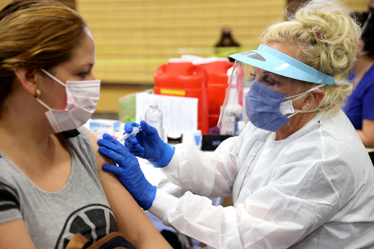 María Pérez de North Las Vegas recibe una vacuna contra la gripe de Lynda McCloskey durante u ...