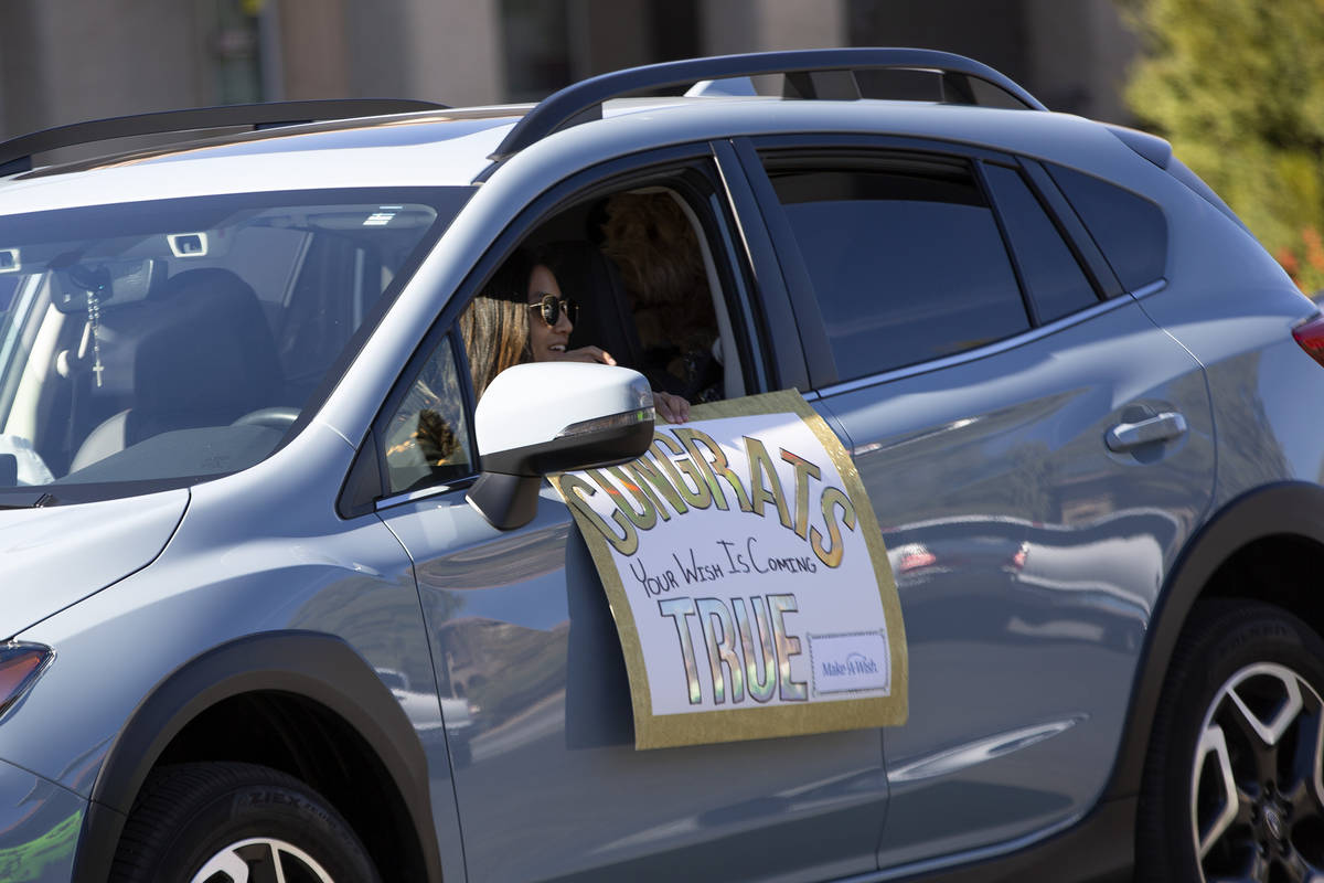 Un desfile de autos pasa por Lauren Cleveland de Las Vegas, quien recibió un nuevo cachorro de ...