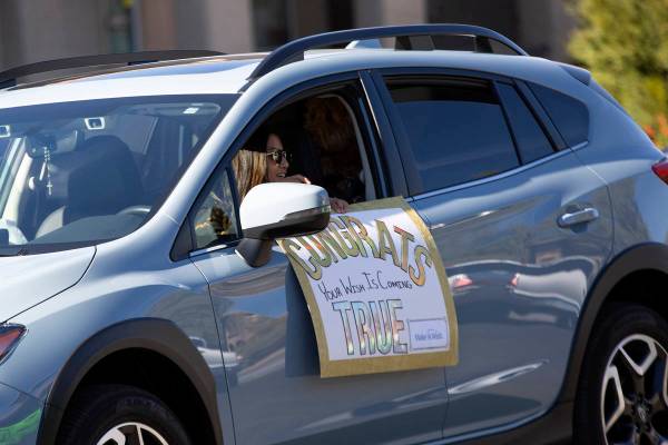 Un desfile de autos pasa por Lauren Cleveland de Las Vegas, quien recibió un nuevo cachorro de ...
