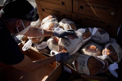 Un voluntario desempaqueta pavos congelados para regalarlos en un evento de distribución de co ...
