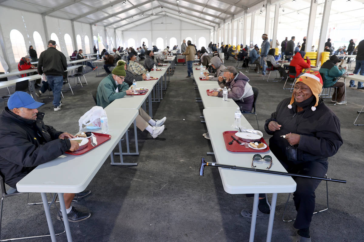 Gente come socialmente distante una comida de Acción de Gracias en el nuevo pabellón al aire ...