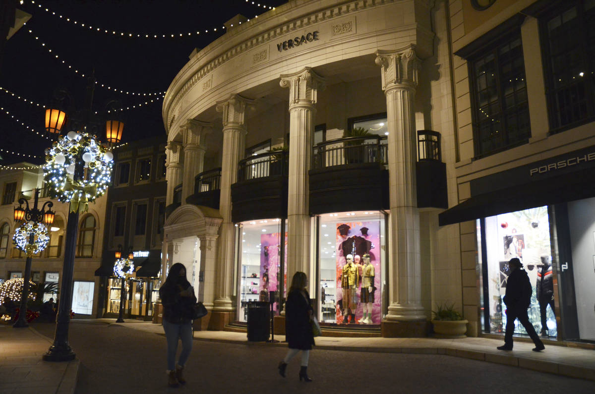 Dos personas pasan por delante de la tienda Versace en Rodeo Drive, la noche del lunes, 30 de n ...