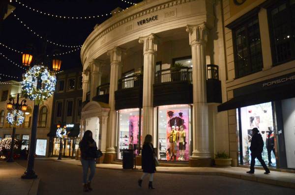 Dos personas pasan por delante de la tienda Versace en Rodeo Drive, la noche del lunes, 30 de n ...