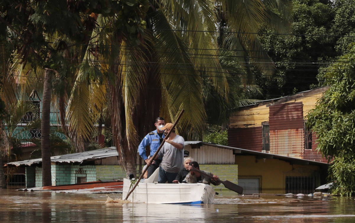 Residentes reman un bote a través de una calle inundada tras el huracán Eta en Planeta, Hondu ...