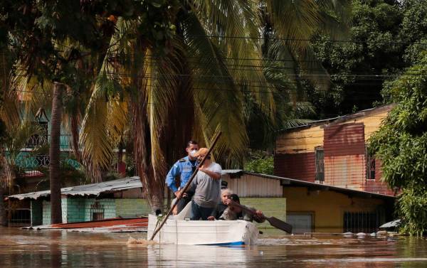 Residentes reman un bote a través de una calle inundada tras el huracán Eta en Planeta, Hondu ...