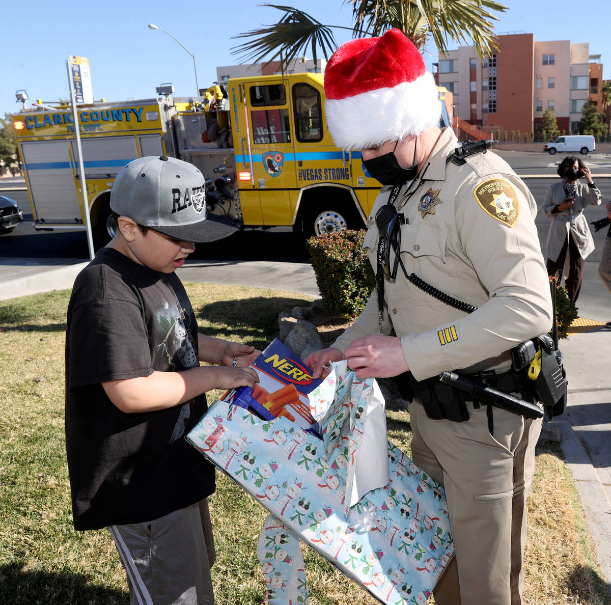 Josh Irwin ayuda a Kevin Salazar, de ocho años, a abrir un regalo durante la caravana de jugue ...