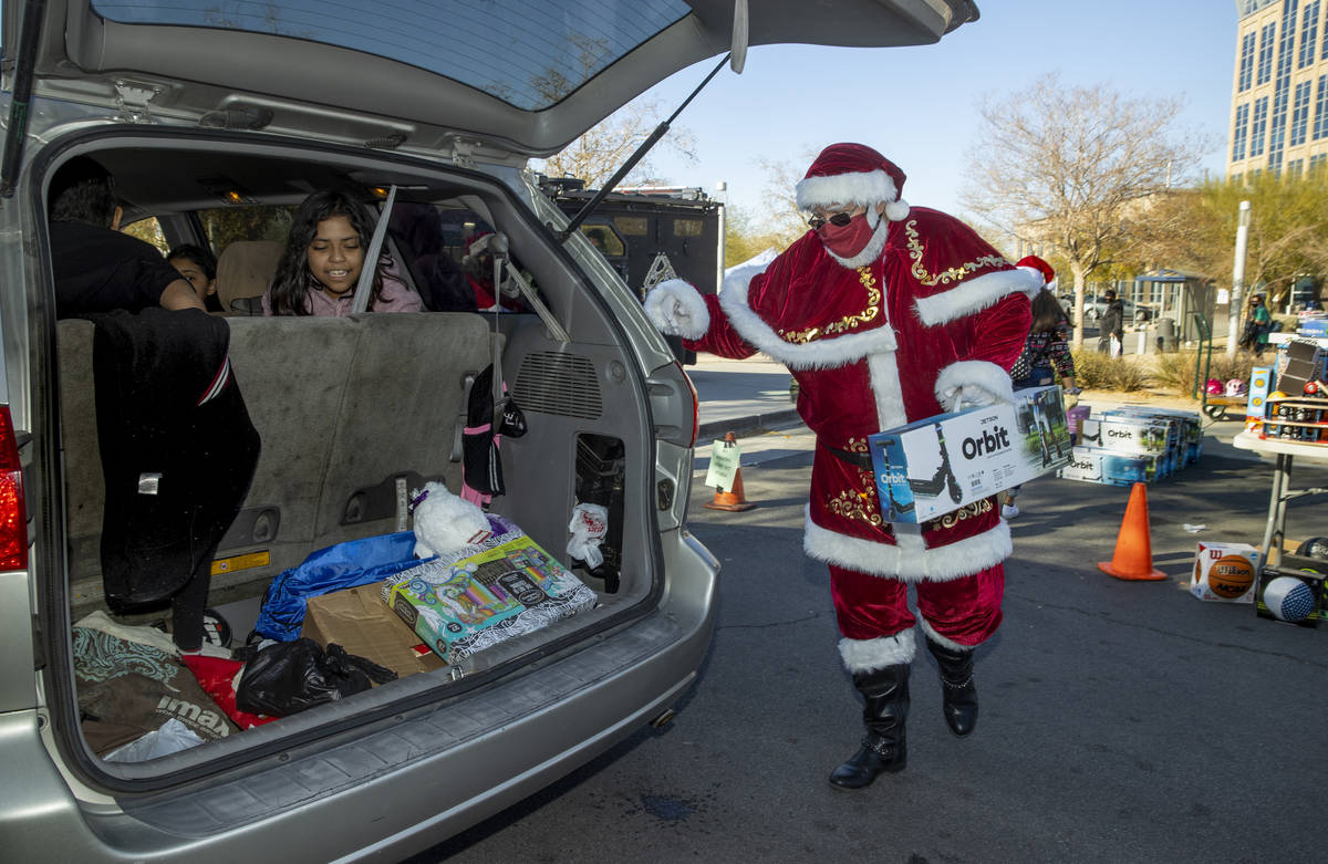 Santa Claus carga regalos durante el primer evento "NLVPD Holiday Toy Giveaway" en el estaciona ...