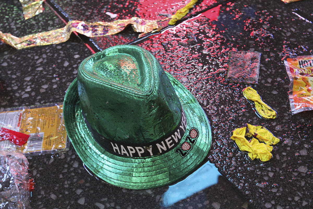 En esta foto de archivo, un sombrero de "Feliz Año Nuevo" yace en el suelo húmedo junto con o ...