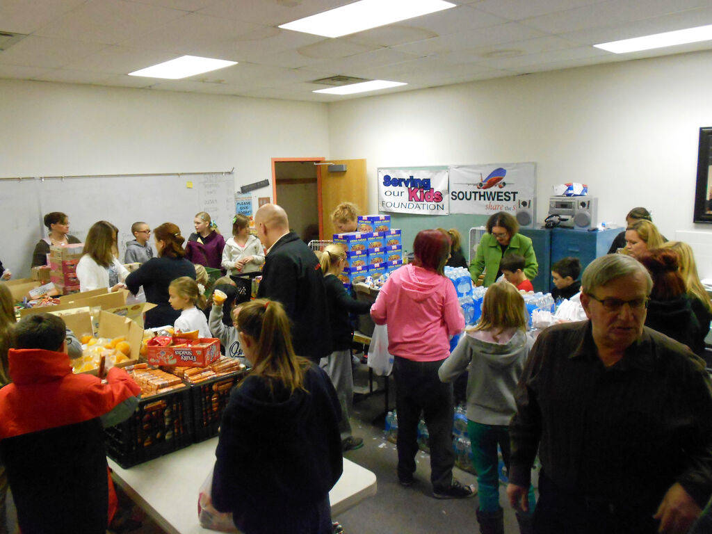 Voluntarios llenan bolsas de comida en el almacén de la Serving Our Kids Foundation. (Linda J. ...