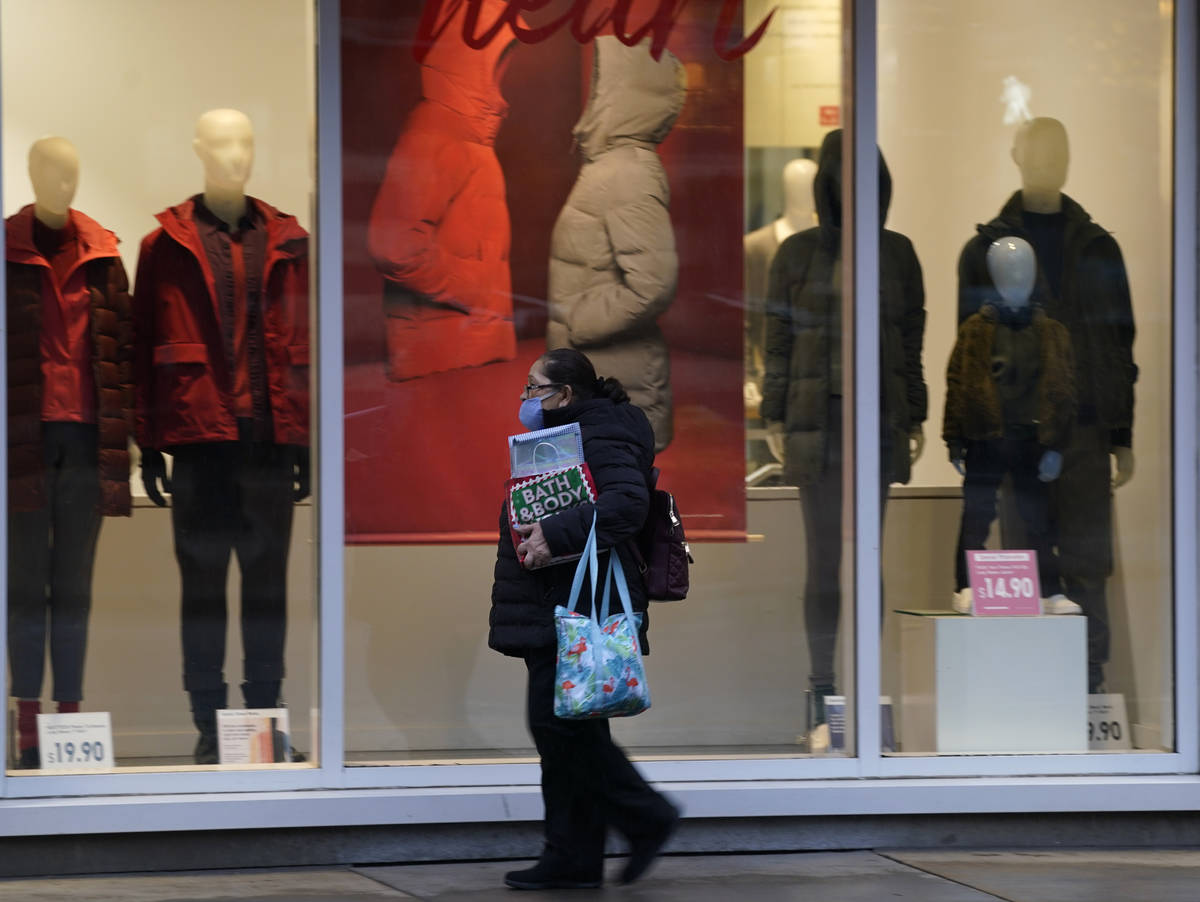 Un peatón usa un cubrebocas al pasar por una vitrina de una tienda de ropa a finales del lunes ...