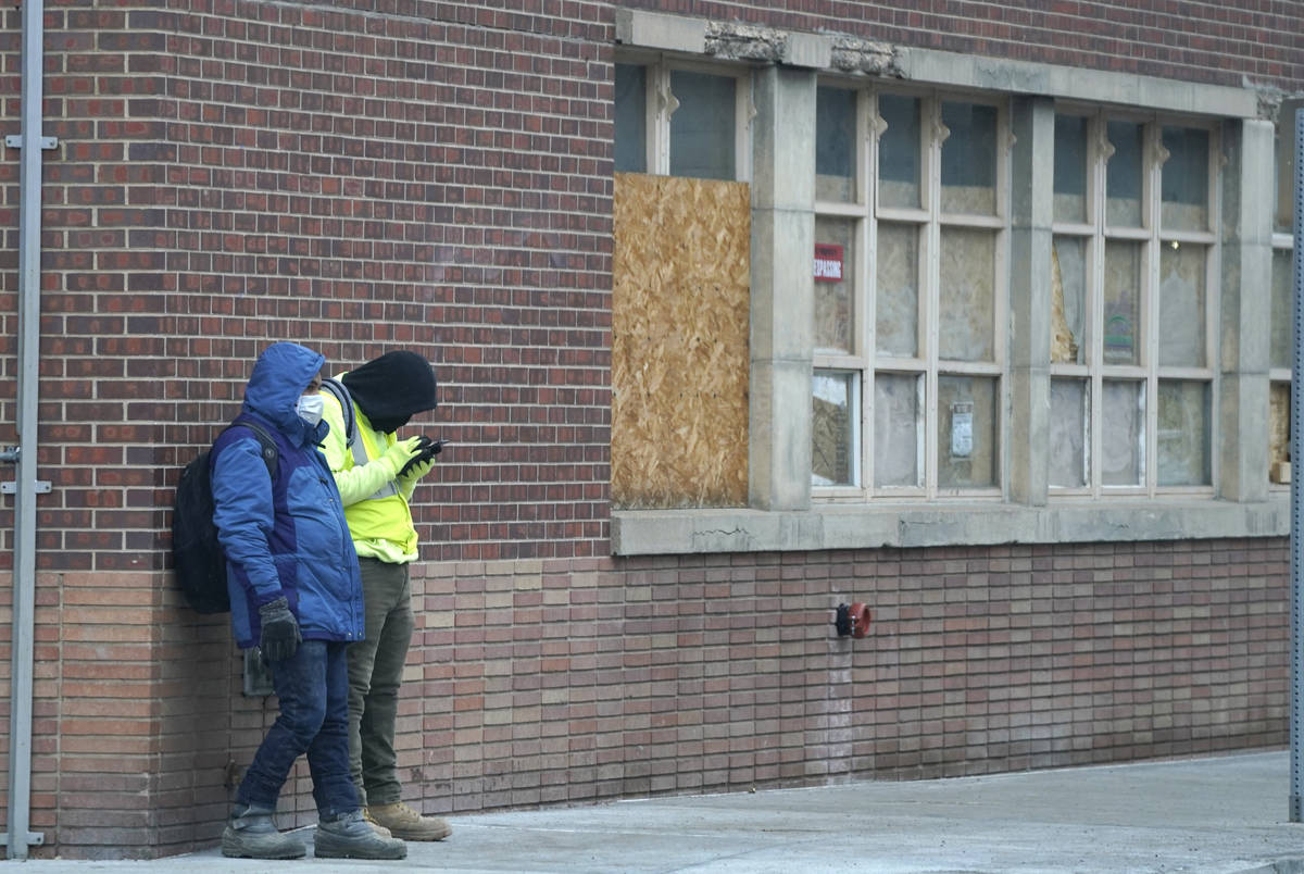 Un par de trabajadores usan cubrebocas mientras esperan un paseo fuera de una obra a finales de ...