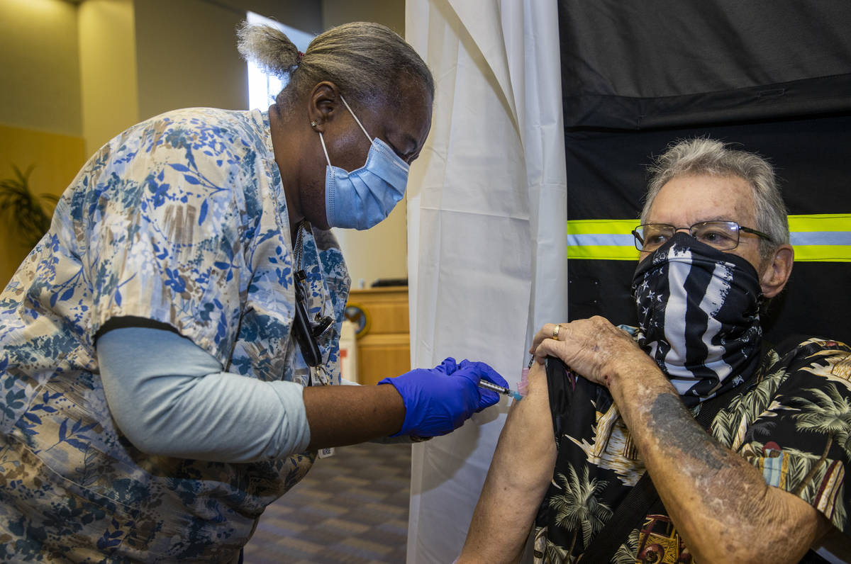 La enfermera Francine Jones-Toliver, a la izquierda, inyecta al veterano George Davis mientras ...