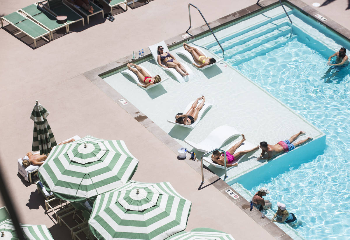 Huéspedes del hotel se relajan junto a la piscina de Park MGM mientras las temperaturas alcanz ...