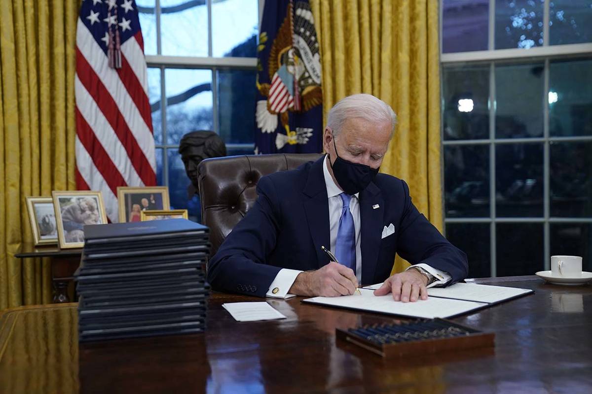 El presidente Joe Biden firma sus primeras órdenes ejecutivas en el Despacho Oval de la Casa B ...