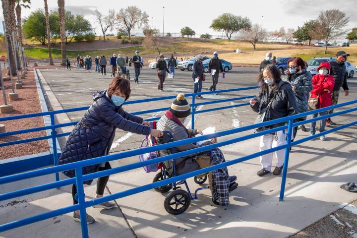 Gente avanza en una larga fila en el estacionamiento de Cashman Center para recibir las vacunas ...