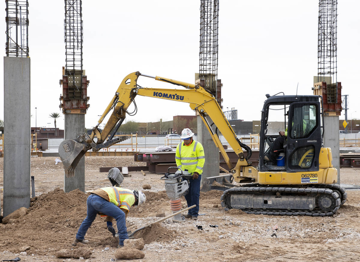 Trabajadores de la construcción utilizan compactadores para reafirmar el suelo en el sitio de ...