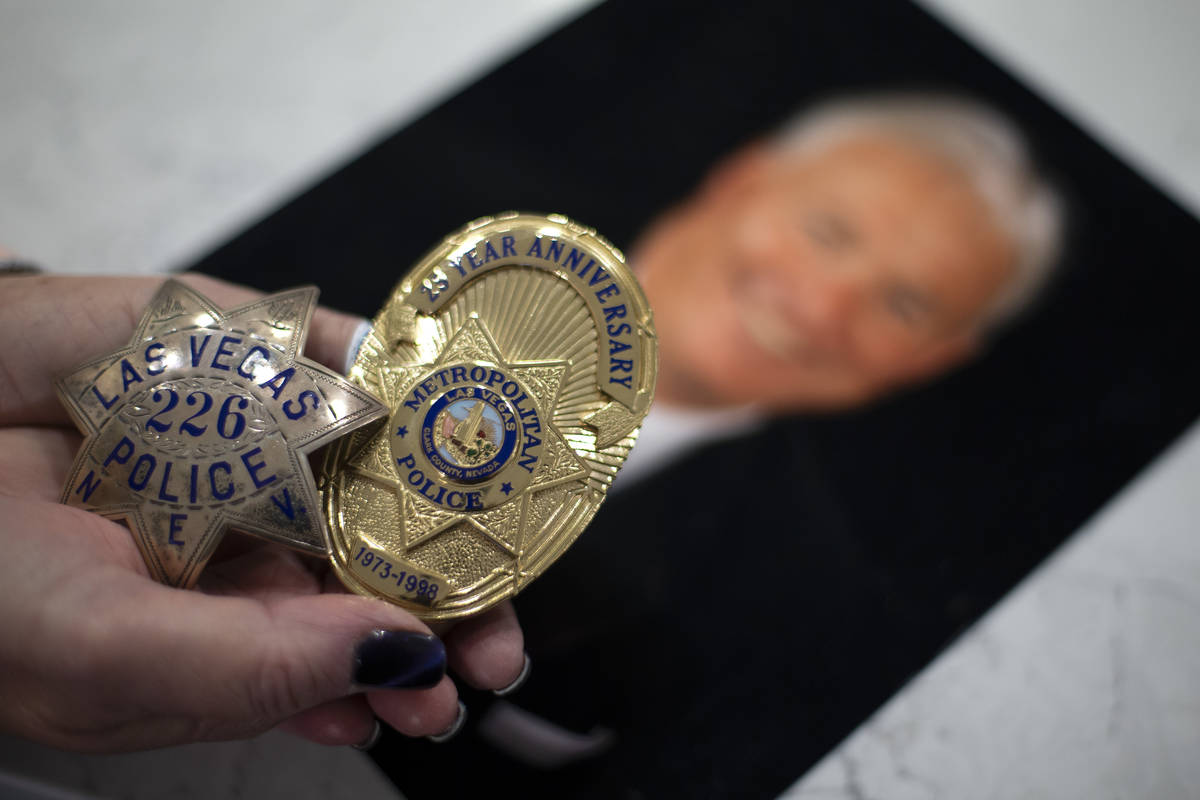 Kathy Karstedt sostiene las insignias de policía de su difunto marido sobre una foto de él en ...