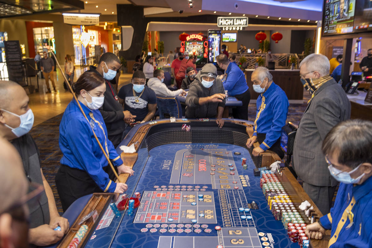 Una mesa de dados está ocupada con jugadores y croupier ya que los casinos ahora pueden acepta ...