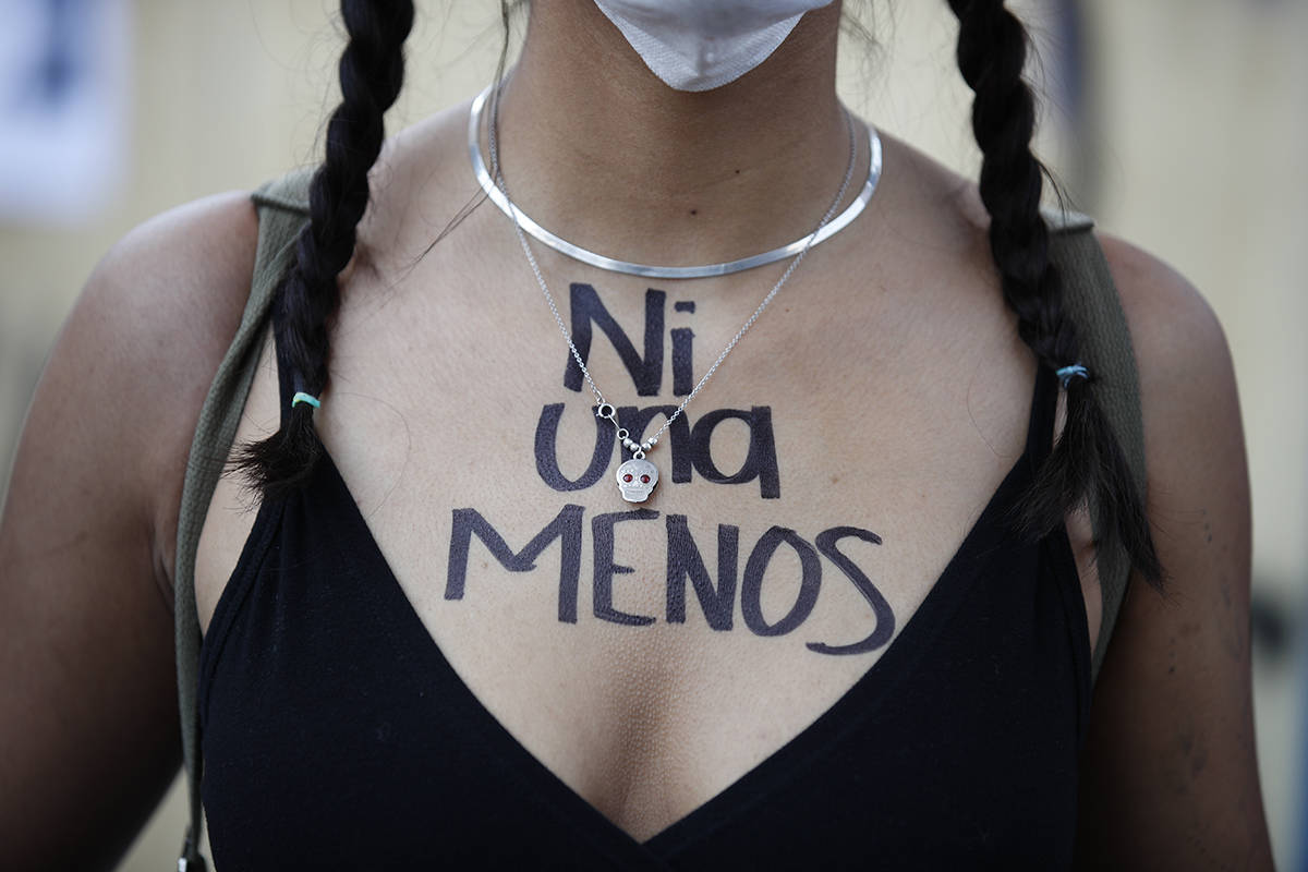 Una mujer con las palabras "Ni una menos" escritas en su pecho en español se une a una marcha ...