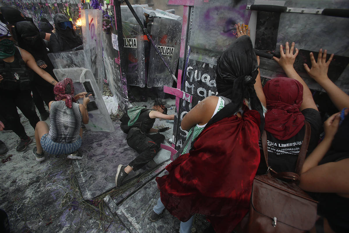 Manifestantes abren una brecha en un muro de protección policial en una barricada que protege ...