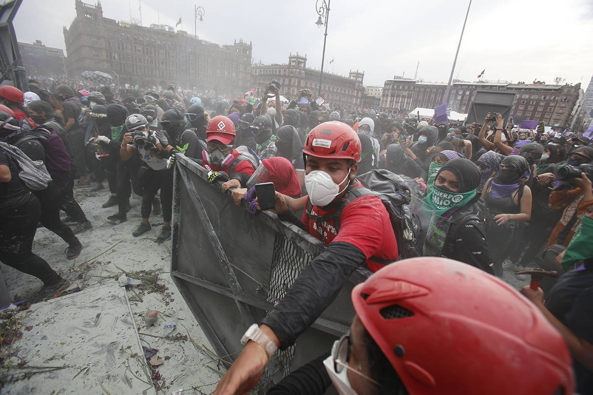 Paramédicos vestidos de rojo, intentan separar a manifestantes que chocan con la policía en u ...
