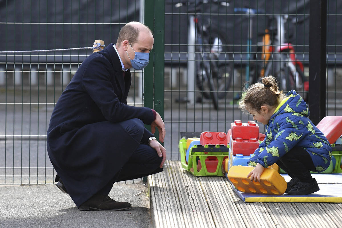 El príncipe británico William habla con un niño en el patio de recreo durante una visita con ...