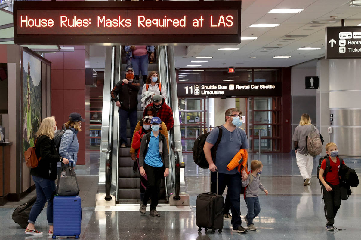 Viajeros enmascarados caminan por la Terminal 1 del Aeropuerto Internacional McCarran en Las Ve ...