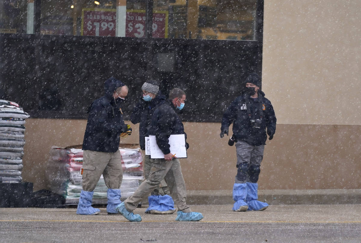 Investigadores se enfrentan a una ligera nevada mientras recogen pruebas en el estacionamiento ...