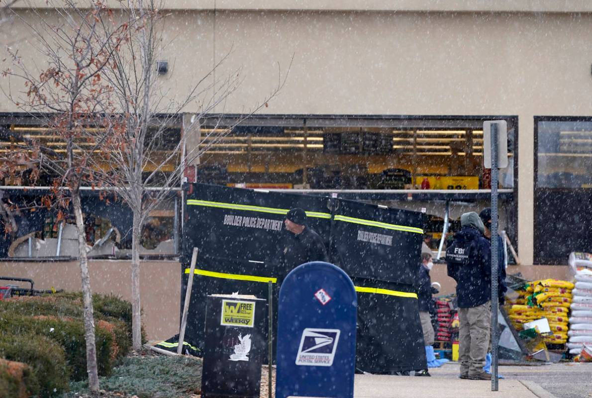 Investigadores se enfrentan a una ligera nevada mientras recogen pruebas en el estacionamiento ...