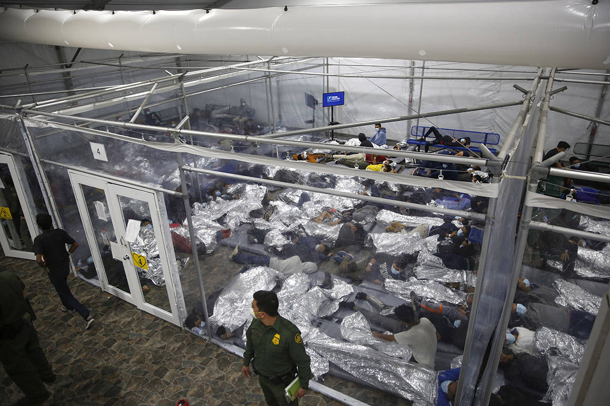 Los niños pequeños se paran o duermen dentro de una cápsula en el centro de detención de Ad ...
