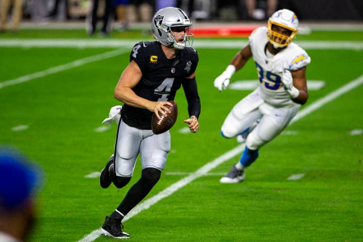 El quarterback de los Raiders, Derek Carr (4), lucha con el balón mientras el cornerback de lo ...