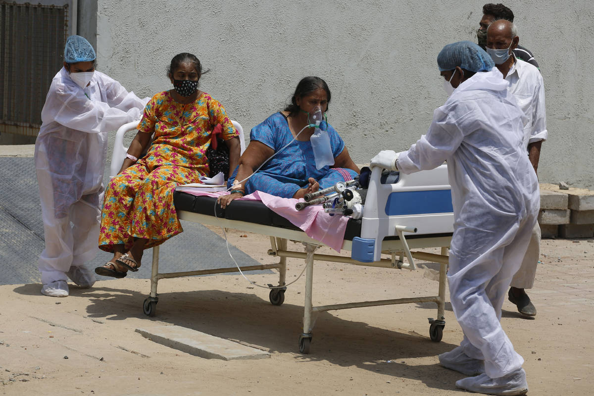 Un trabajador de salud lleva a pacientes para trasladarlos de un hospital dedicado al COVID a o ...
